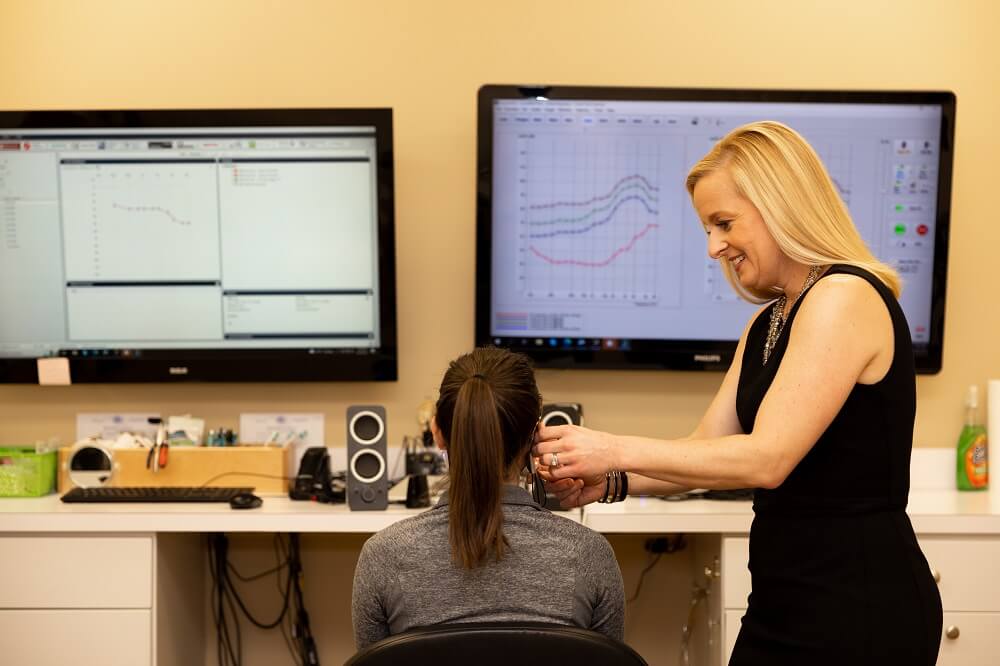 Briana Bruno Holtan, Au.D. examining ears of a patient during hearing assessment